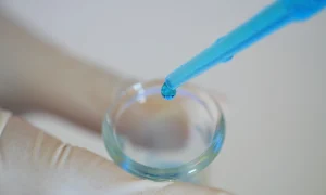 Pipeta de laboratorio depositando una muestra líquida en un recipiente de vidrio durante un procedimiento de reproducción asistida.